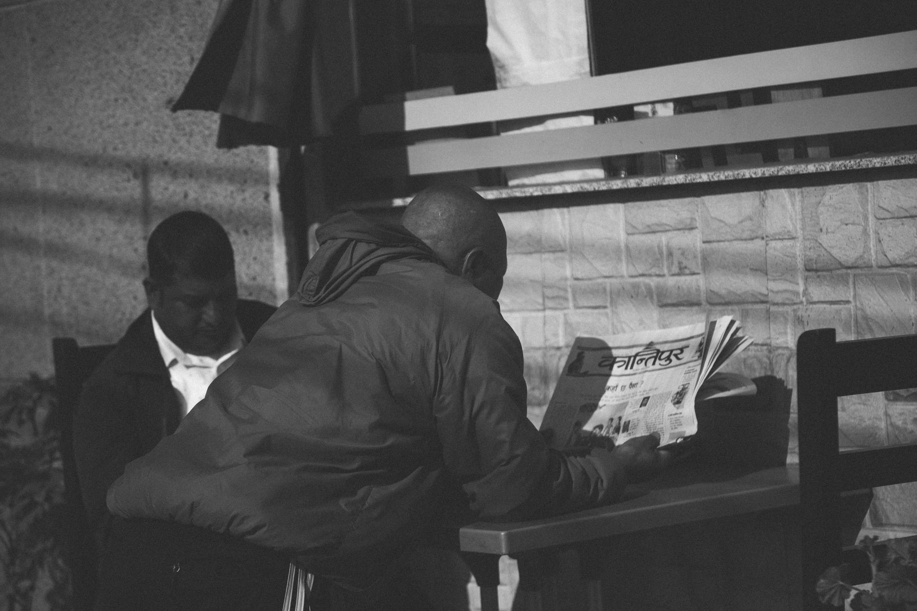 Black and white photo of a man reading a newspaper at an outdoor café in Pokhara, Nepal. — Chasing Clouds: Madrid's Most Enth