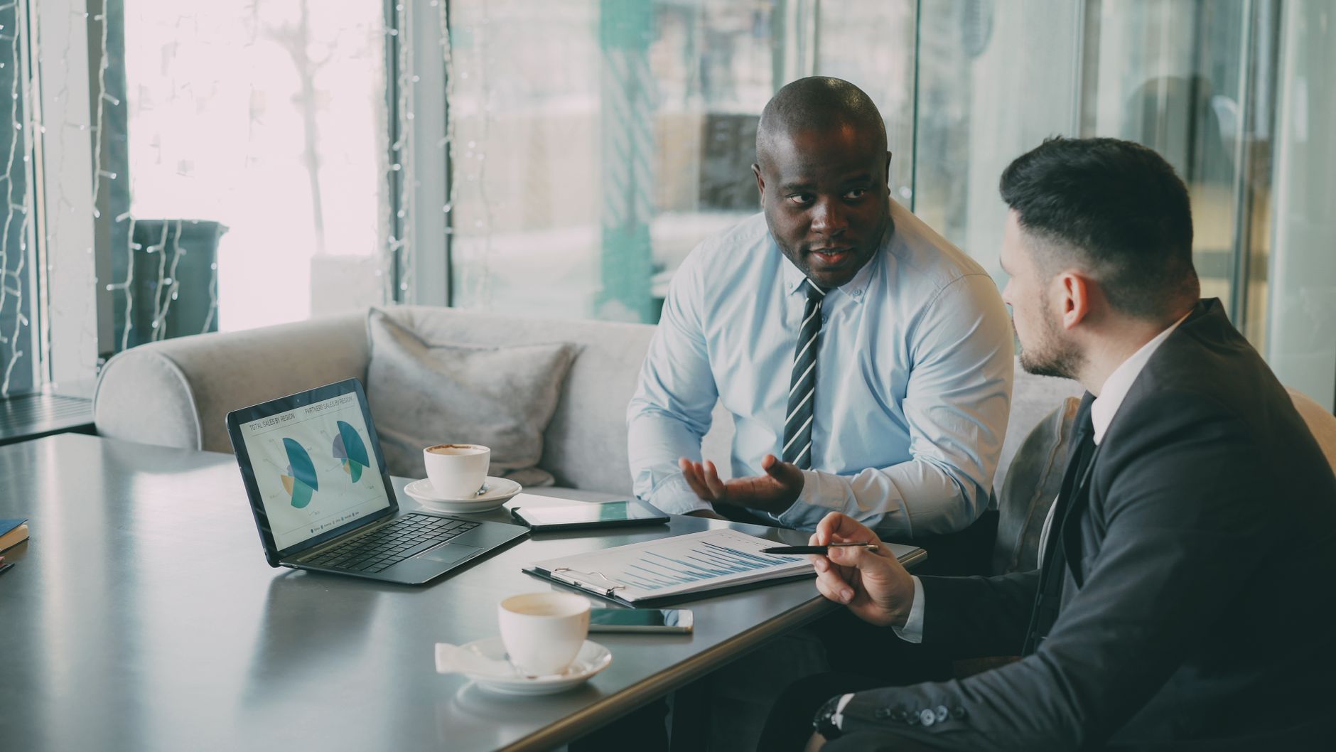 Two business professionals engaged in discussion over laptops and documents. — Choosing the Best Survival Food from Freeze Dr