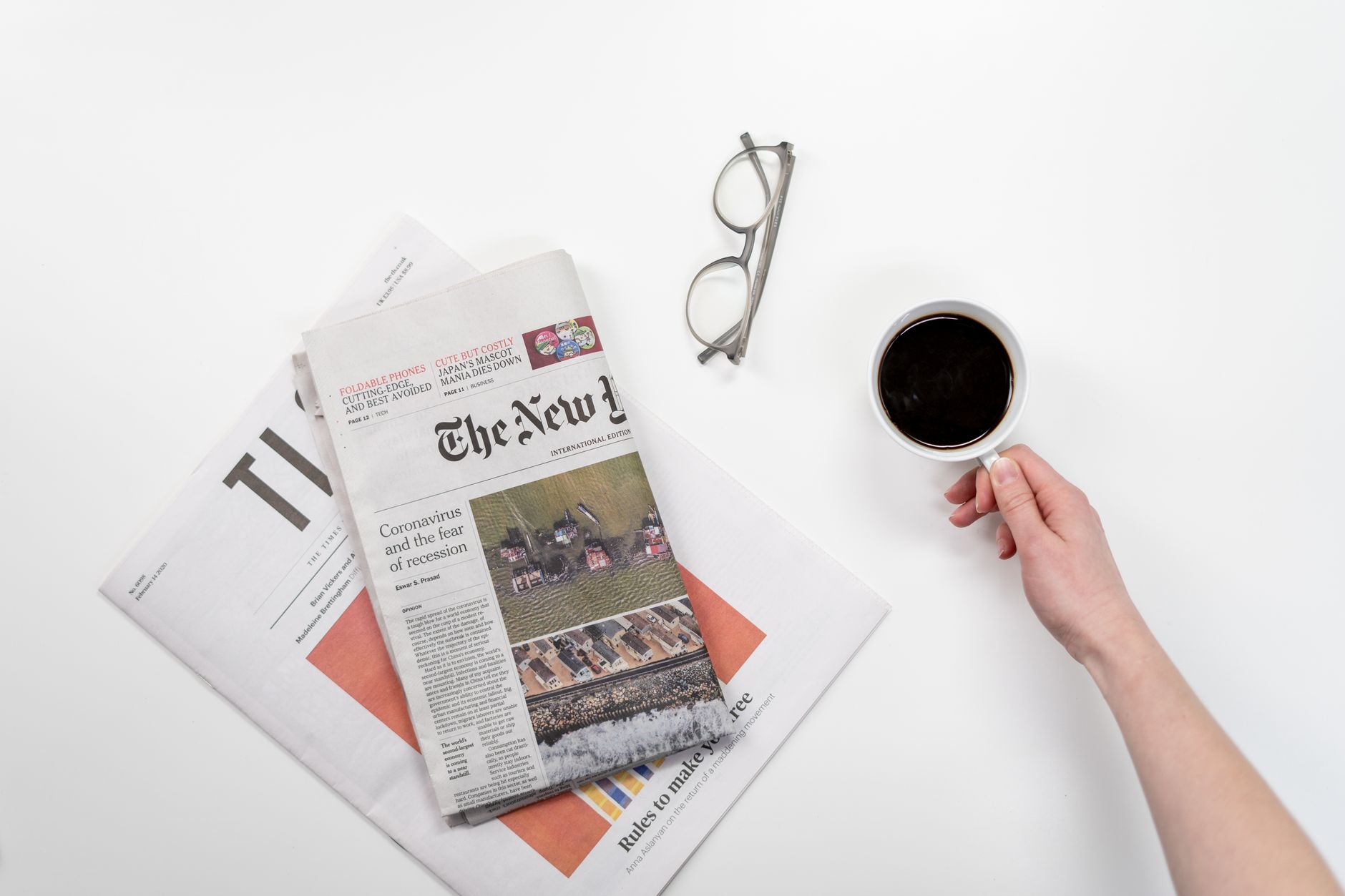 Top view of a coffee cup, newspapers, and eyeglasses on a clean white desk — Comparative Analysis: Microsoft Surface Pro 8 vs