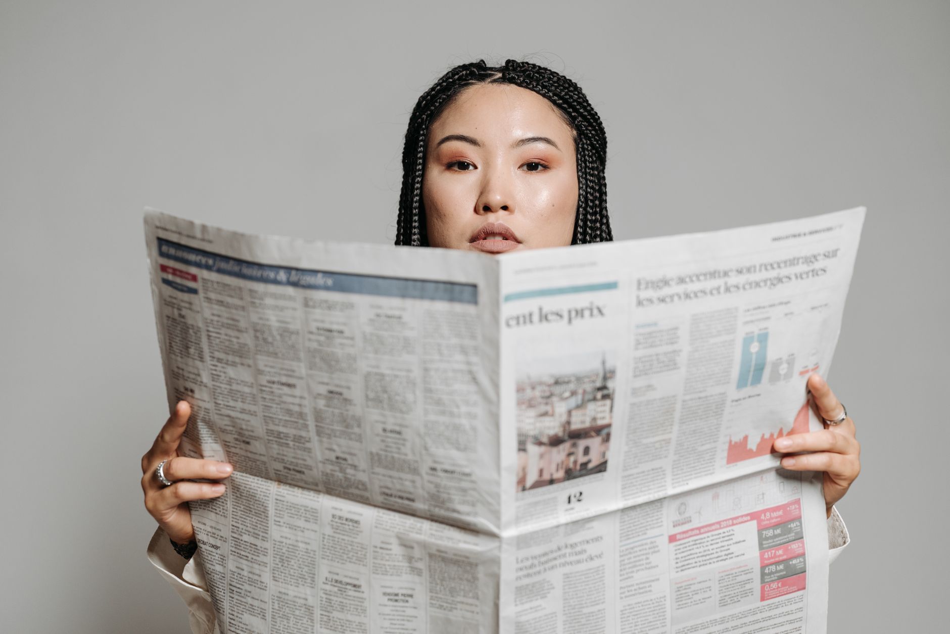 Asian woman with braided hair reading a newspaper in a studio setting. — Crafting a Winning Cover Letter: Simplified