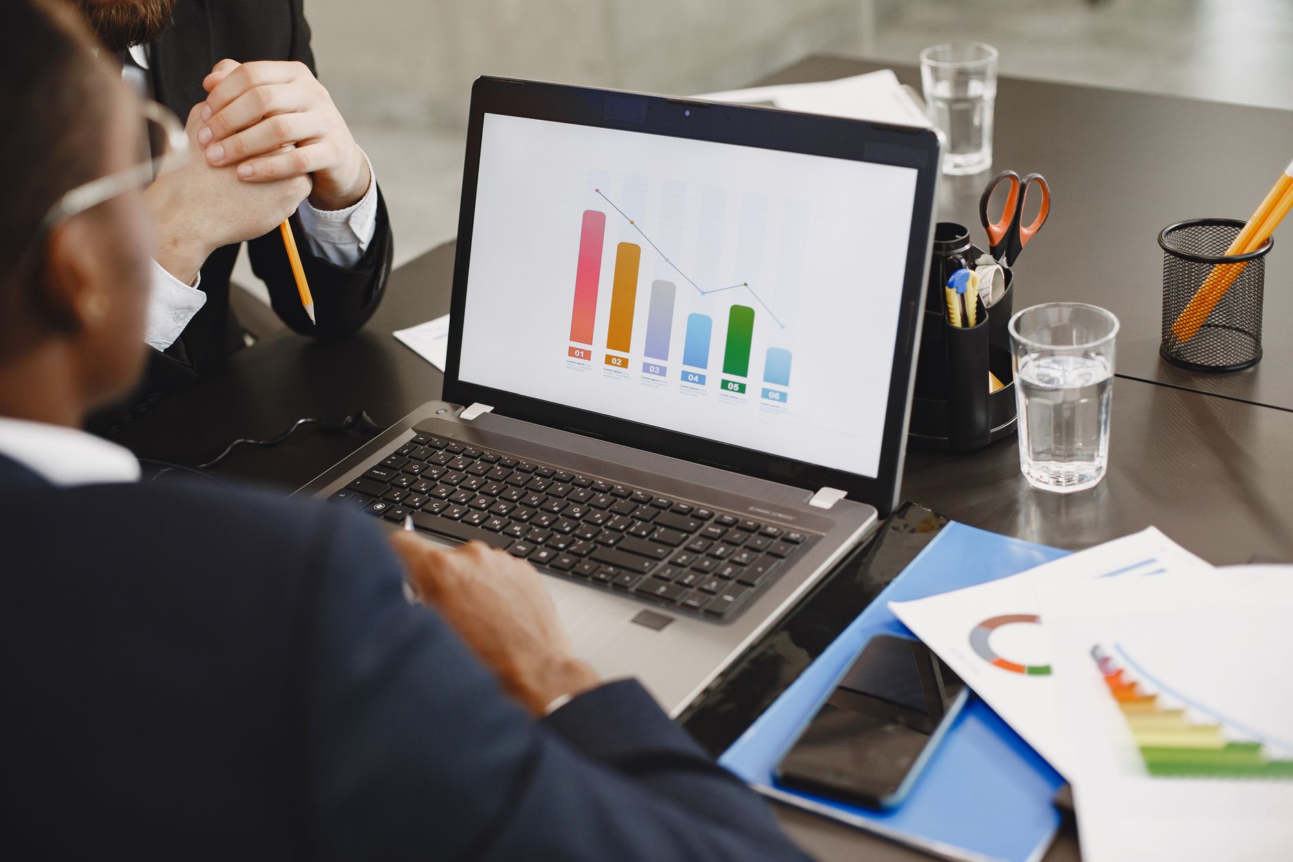 Two professionals analyzing a business graph on a laptop during a meeting. — Effective PP Recycling Practices for a Greener T