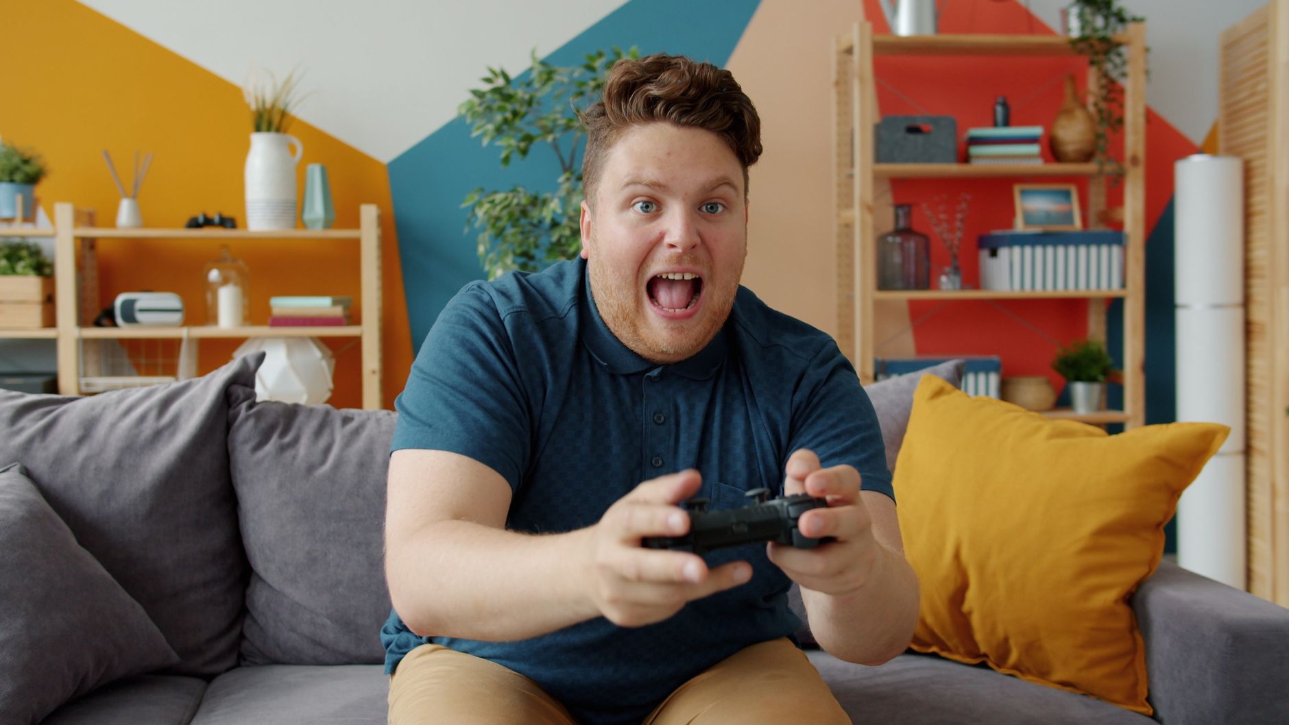 Enthusiastic adult male playing video game on console in colorful, modern living room. — Embracing the Future: The Upsides of