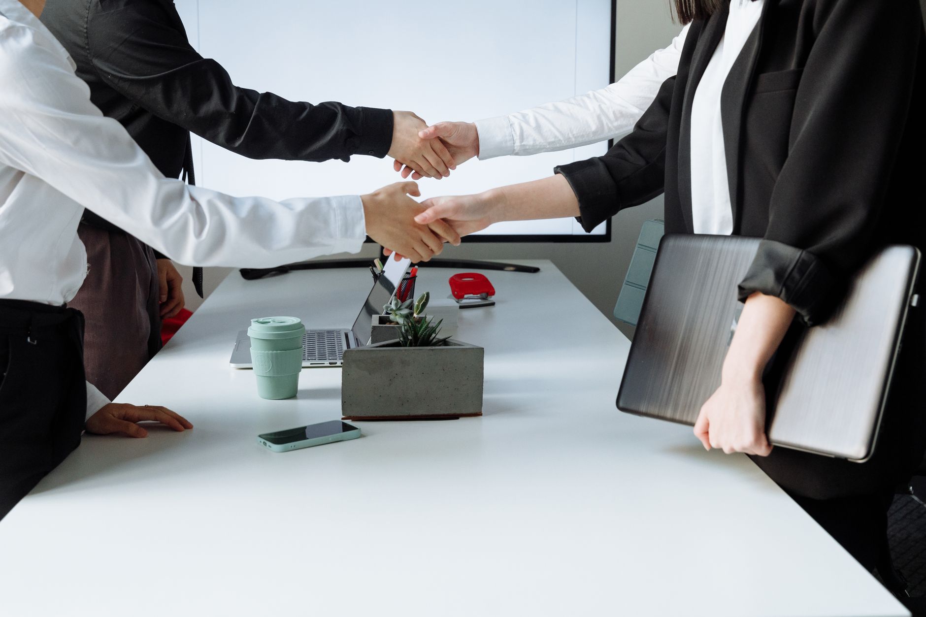 Professionals sealing a deal with a handshake across a conference table during a business meeting. — Experience Perfectly Coo