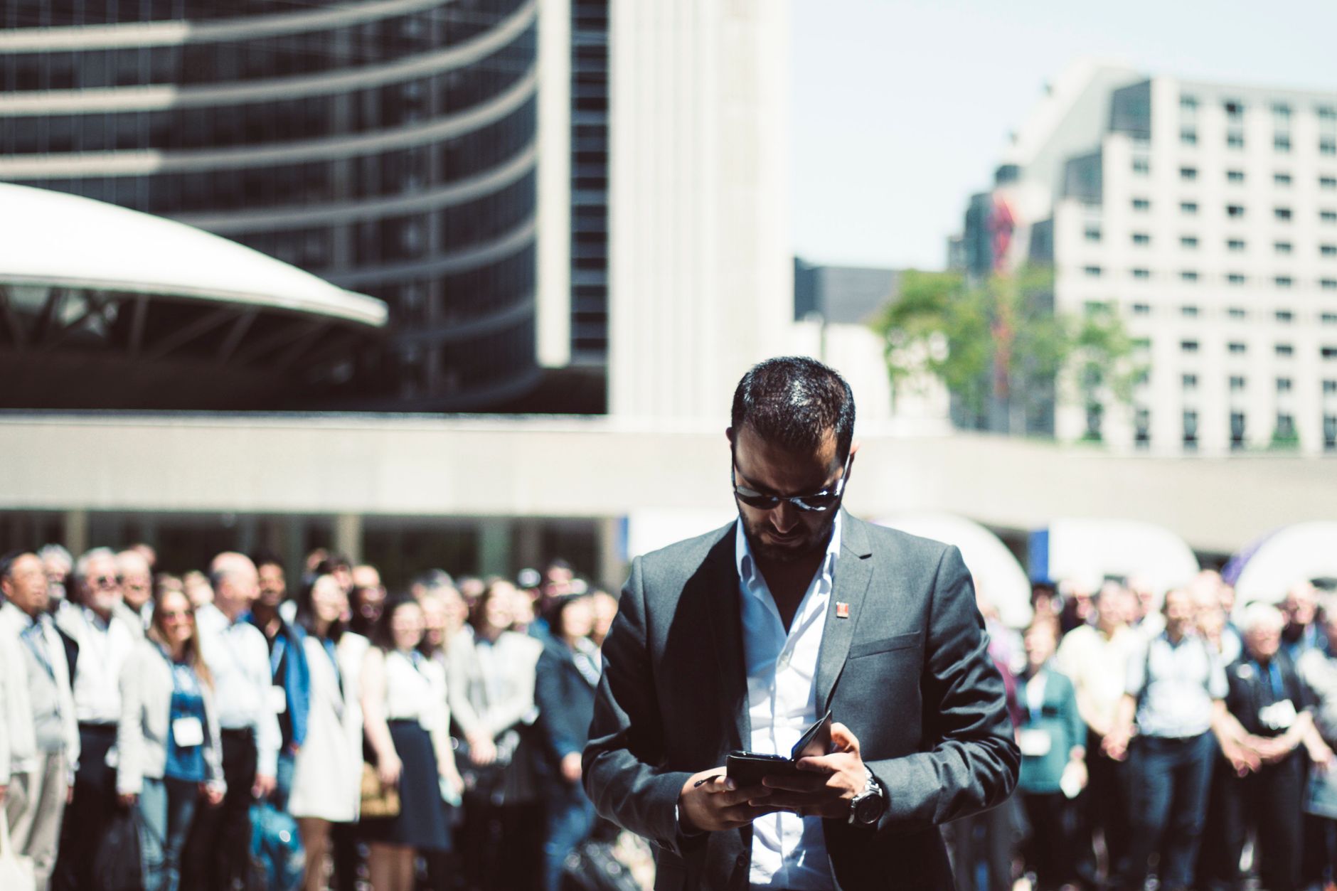 Focused businessman using tablet in a bustling crowd in Toronto's busy urban setting. — Exploring the Many Benefits of Incorp
