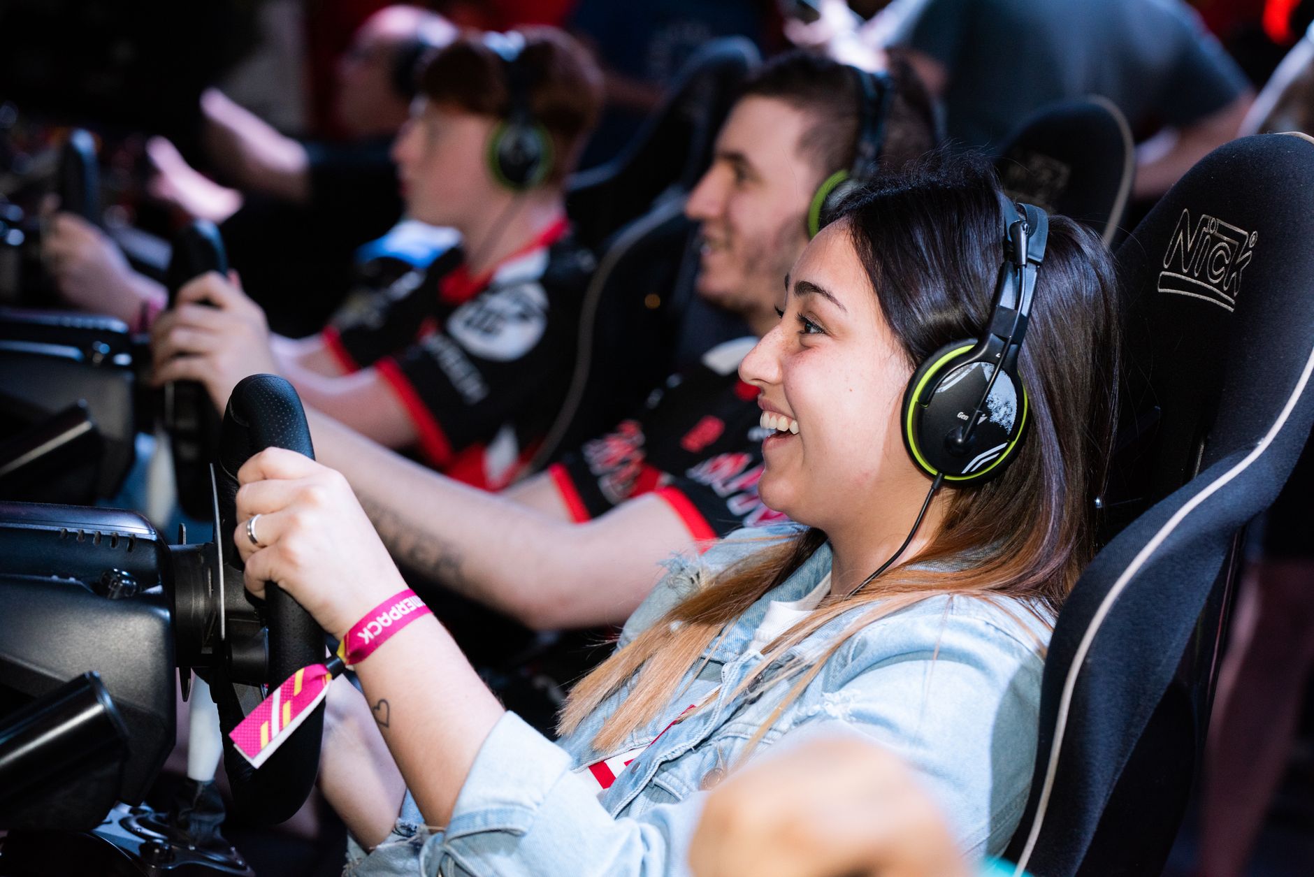 A group of people enjoying an immersive gaming experience at an e-sports center with headphones and steering wheels. — Find Y