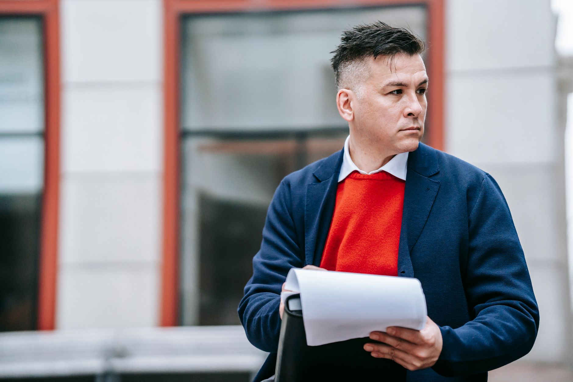 A serious man holding papers, dressed professionally in an urban environment. — Harold Matzner: The Man Behind The American R