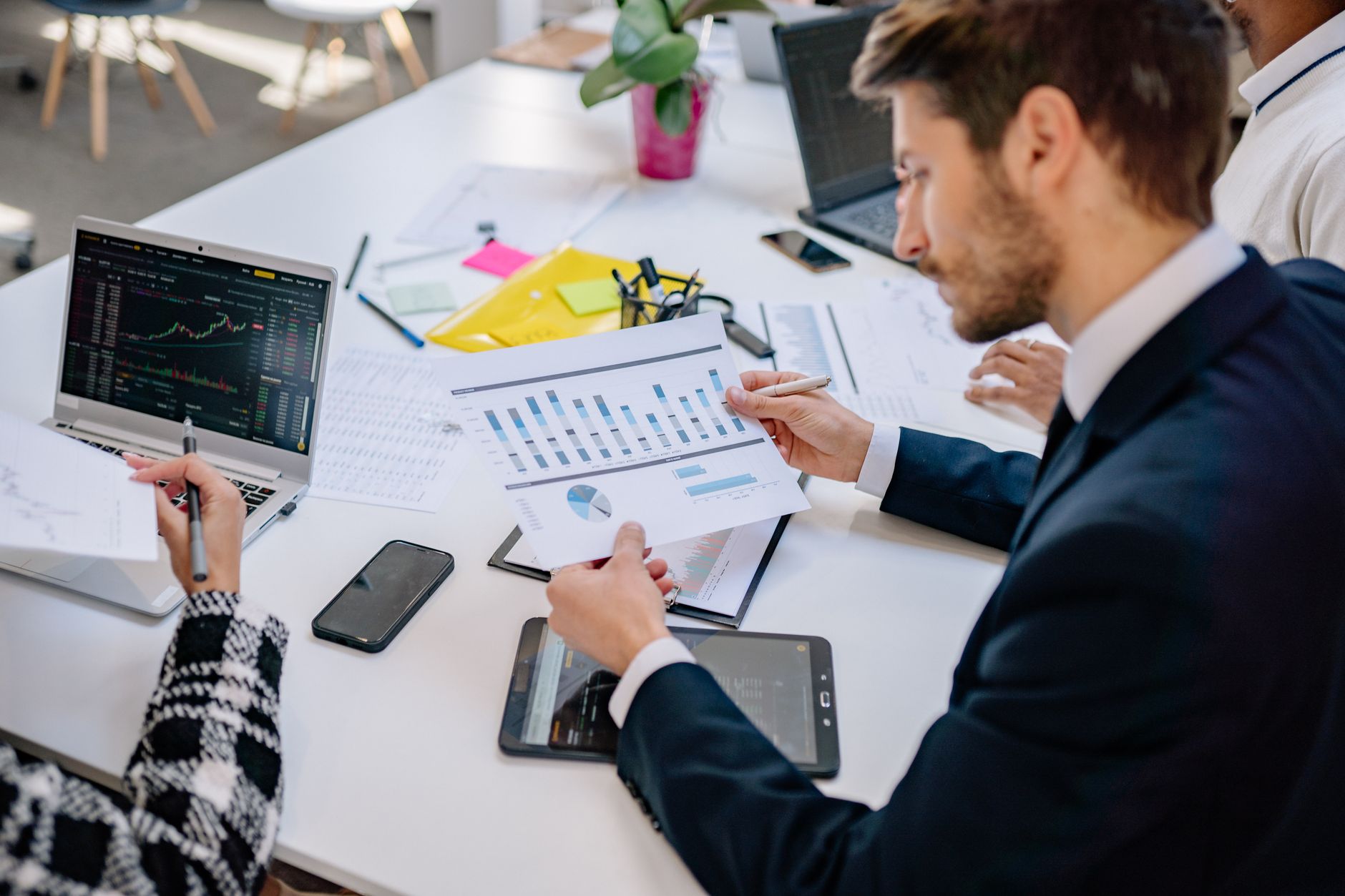 Business team reviewing graphs and data in an office setting. — How a Franchise Consultant Benefits a Franchisor and Potentia