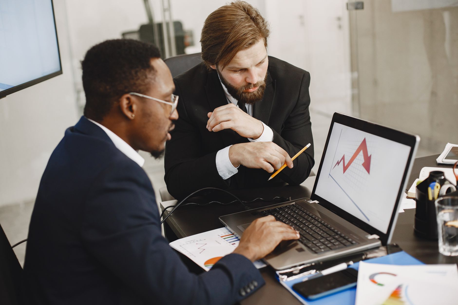 Two business professionals discuss marketing data on a laptop in a modern office. — How Homework Assistance Websites are Revo