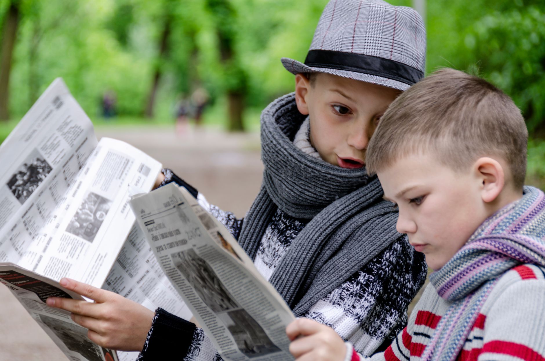 Two young boys reading newspapers together in a lush green park in Lviv, Ukraine. — How To Find An aa rochester Meeting Near