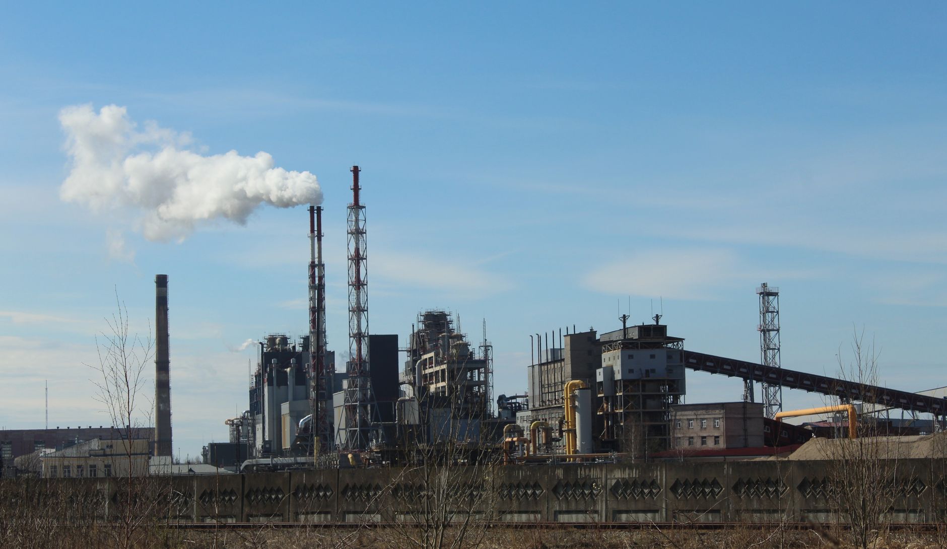 Photo capturing an industrial factory with smokestacks emitting smoke under a clear blue sky. — How To Use A Laser Alignment