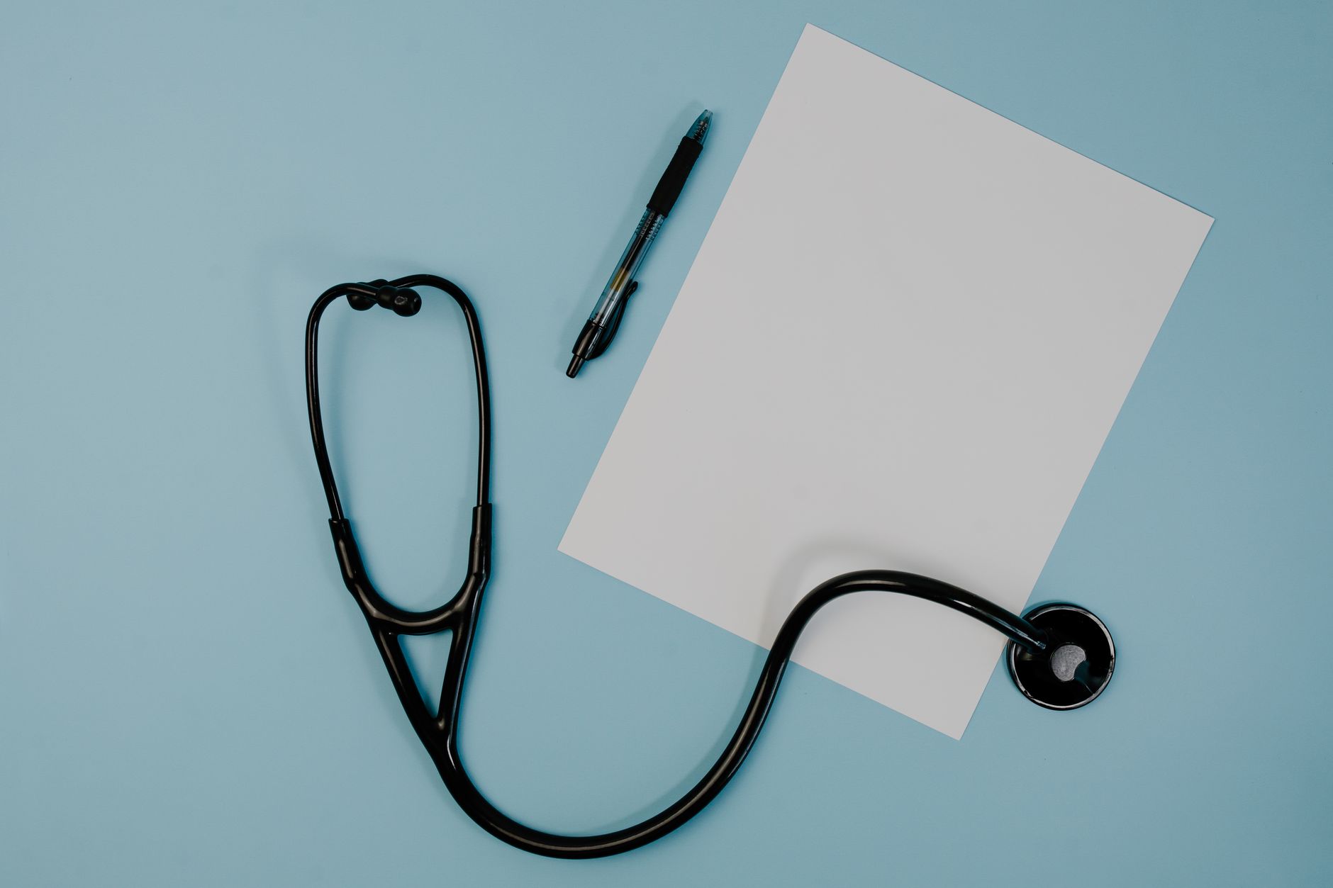 Flat lay of stethoscope, blank paper, and pen on blue surface — Is IQ Test Online Useful?