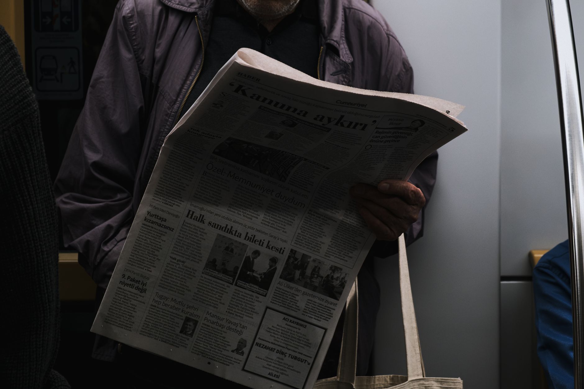 A man reads a newspaper in a dimly lit public transport setting, reflecting city life. — Mastering Public Perception: A Top-T