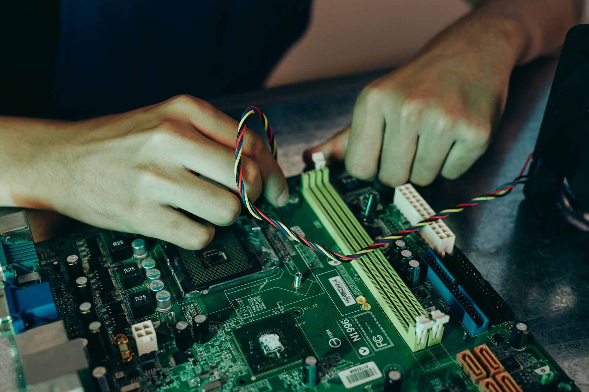 Person assembling computer motherboard with colorful wires, showcasing technology and engineering. — Maximizing Your Online V