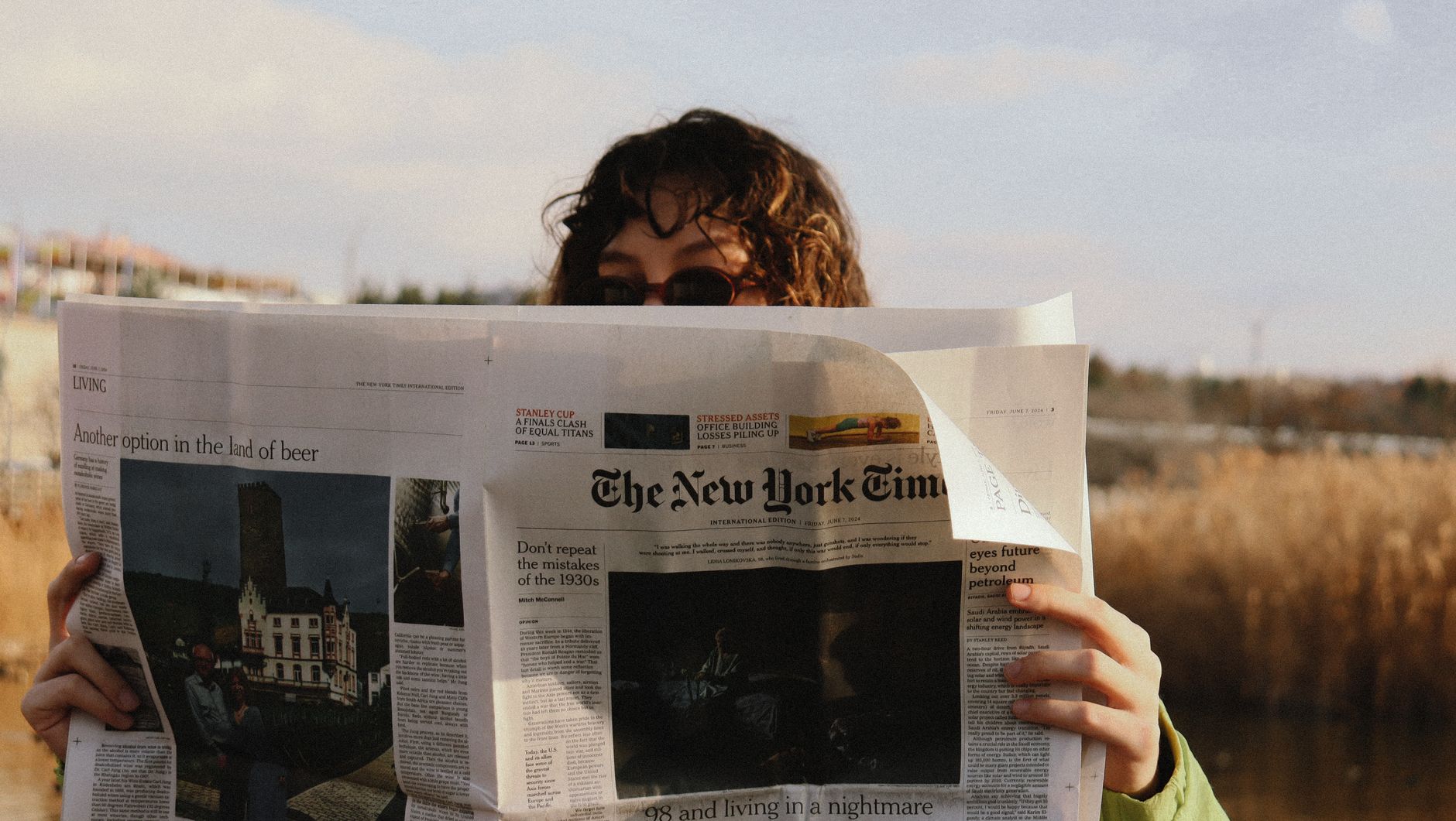 A person reads The New York Times outside on a sunny day, capturing a moment of leisure. — NBA Live Stream: Don't Miss a Sing
