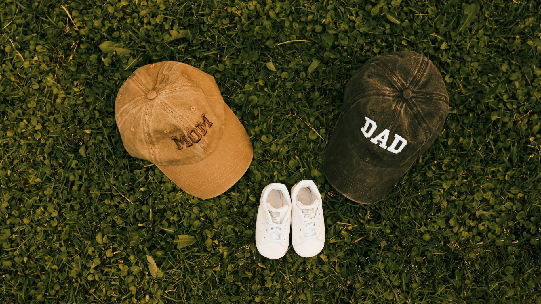 Unique family announcement concept with 'Mom', 'Dad' caps and baby shoes on grass. — Play, Win and Have Fun with Mega Wheel P