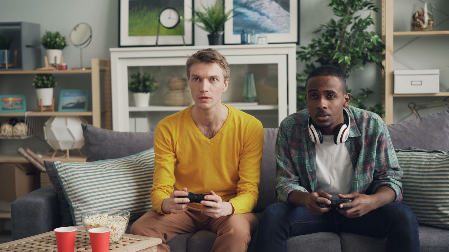 Two friends focus on gaming while relaxing on a couch in a modern living room. — Playing Smart: A Guide to LSM99 Casino Onlin