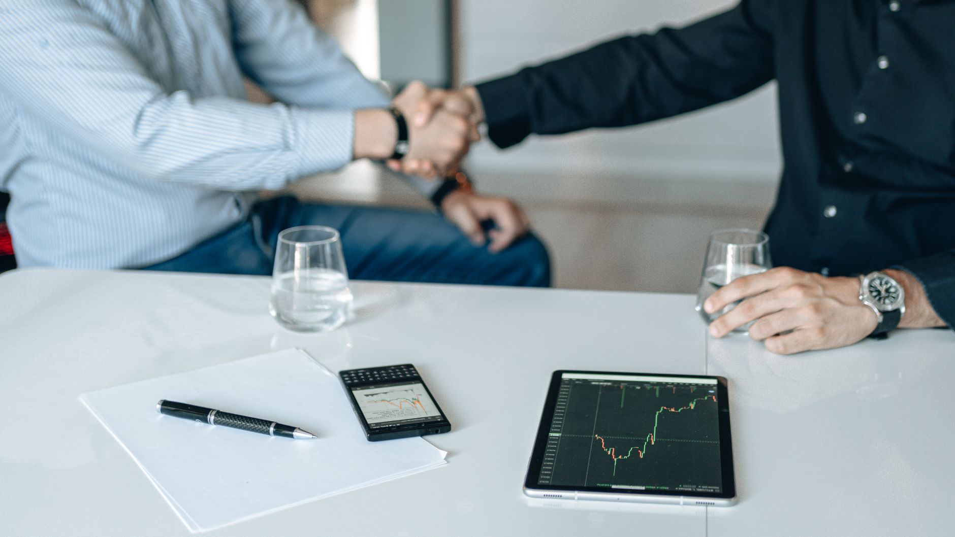 Business meeting with handshake and financial analysis displayed on a tablet. — Refresh Your Mind and Body on Your Next Busin