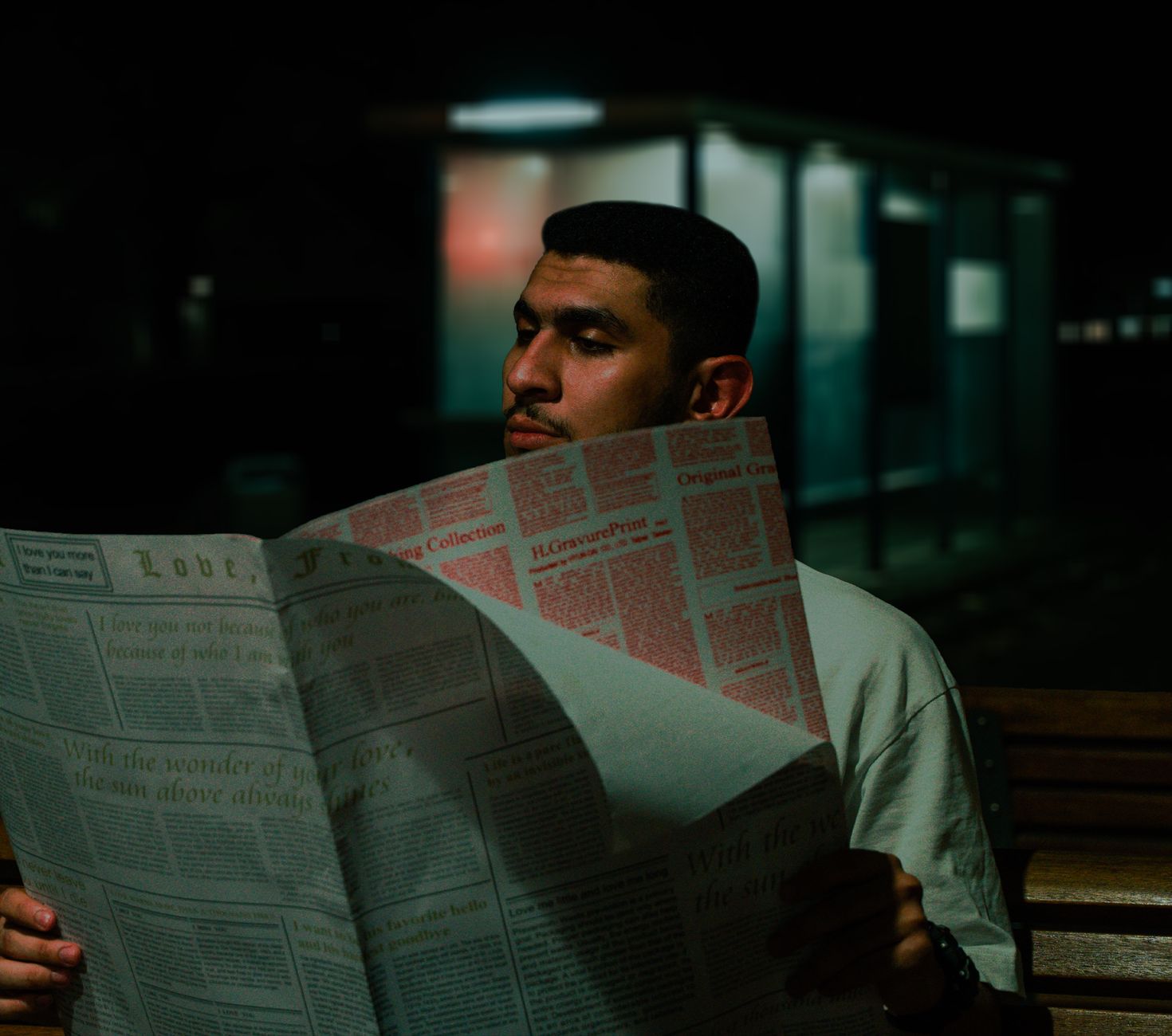 A man reads a newspaper at night on a bench, surrounded by urban darkness. — Rick Littlefield Discusses How Educational and P