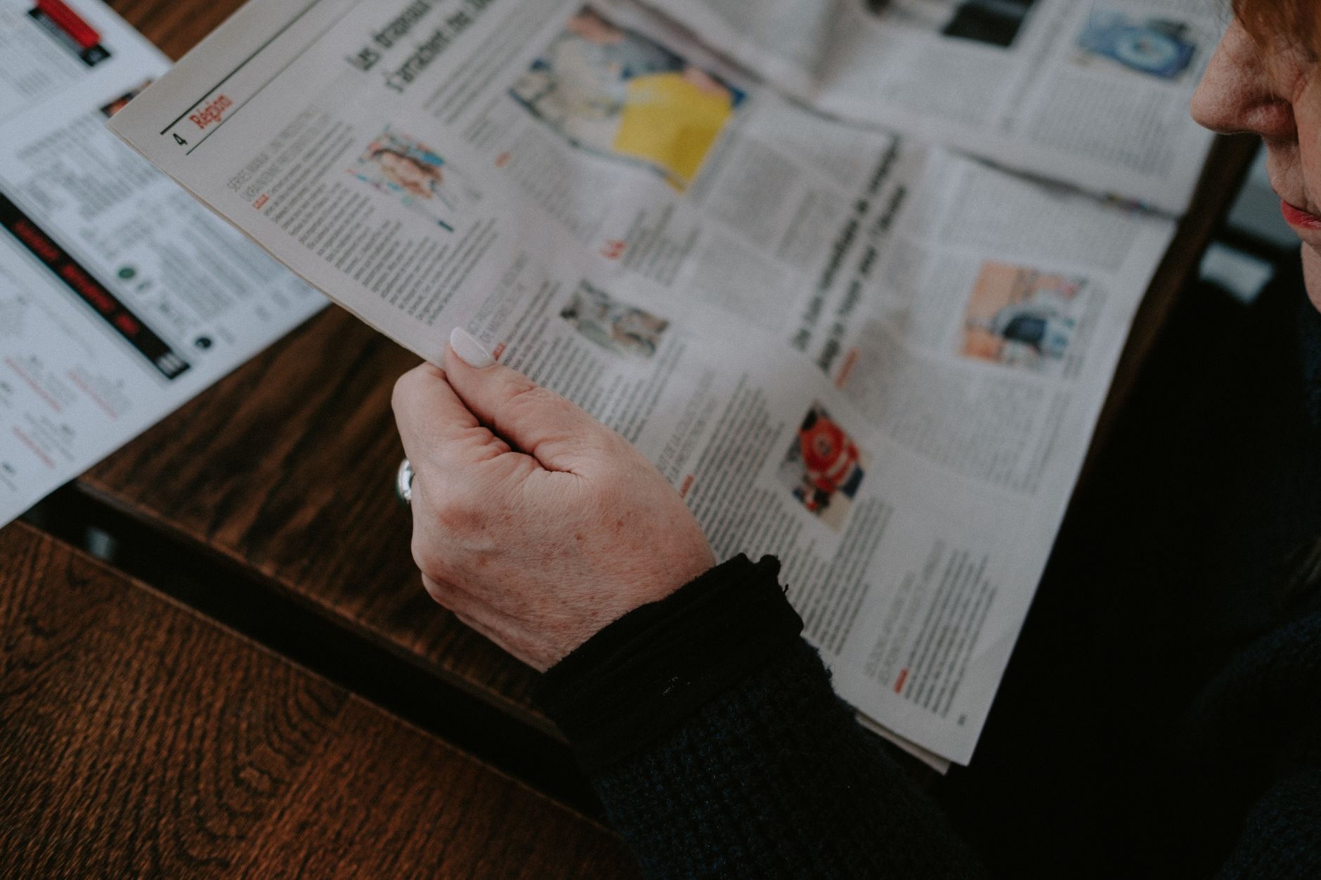Adult reading a newspaper indoors. Captures focus and interest. — StreamEast Live: Breaking Down Barriers in Sports Streaming