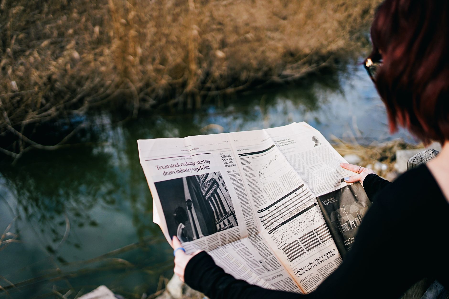 A woman reads a newspaper by a river surrounded by autumn foliage. — Splendid Designs & Fabulous Collections: Uni