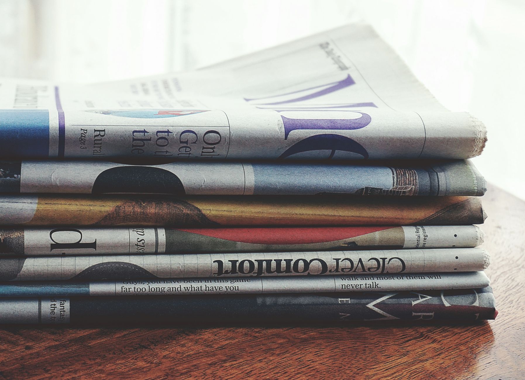 A stack of folded newspapers placed on a wooden table, symbolizing news and information. — Target Local Customers wit