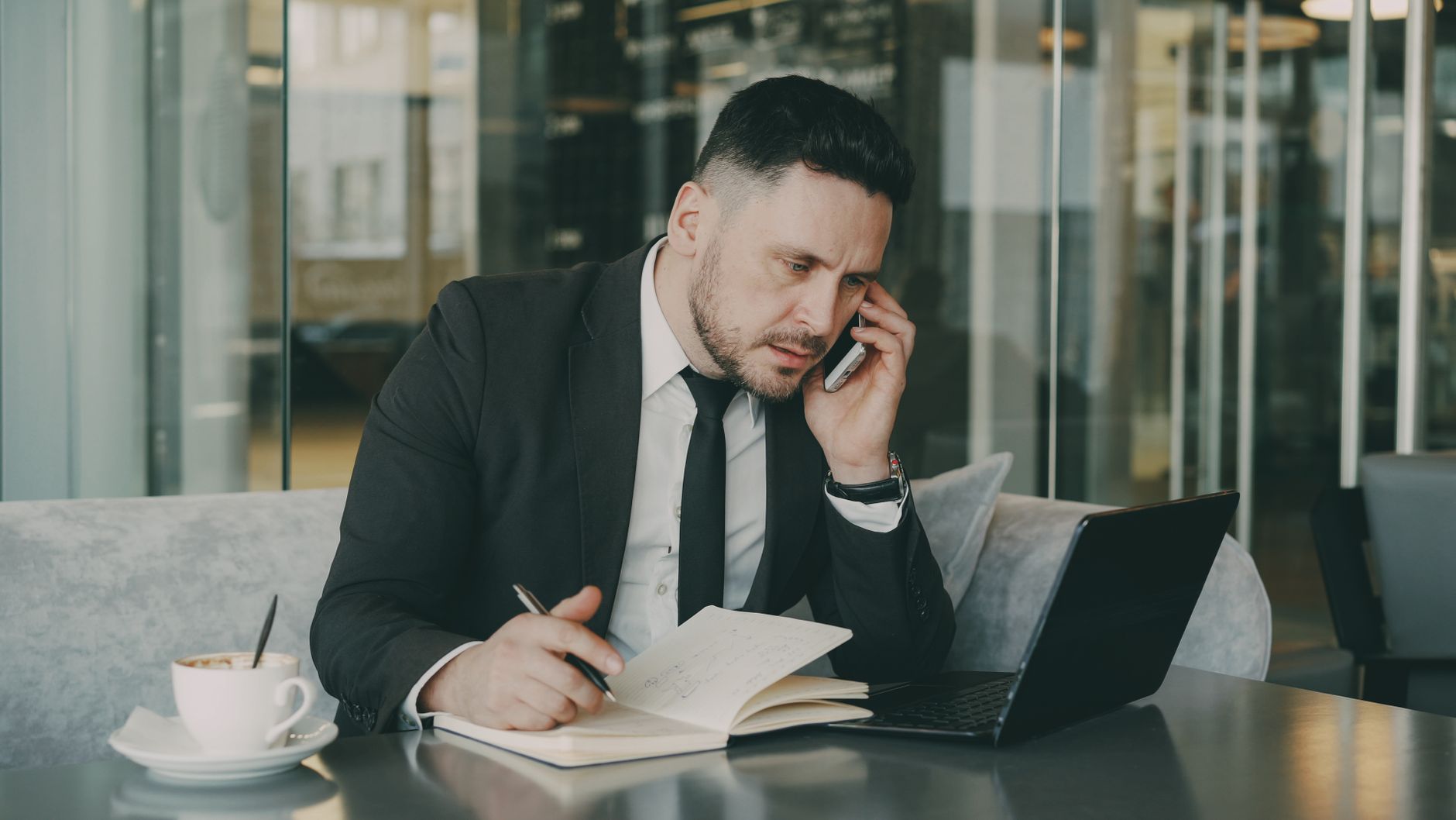 Businessman talks on phone while writing notes in a modern cafe. — Unleash the Inner Diva in You: Find a Great Karaok