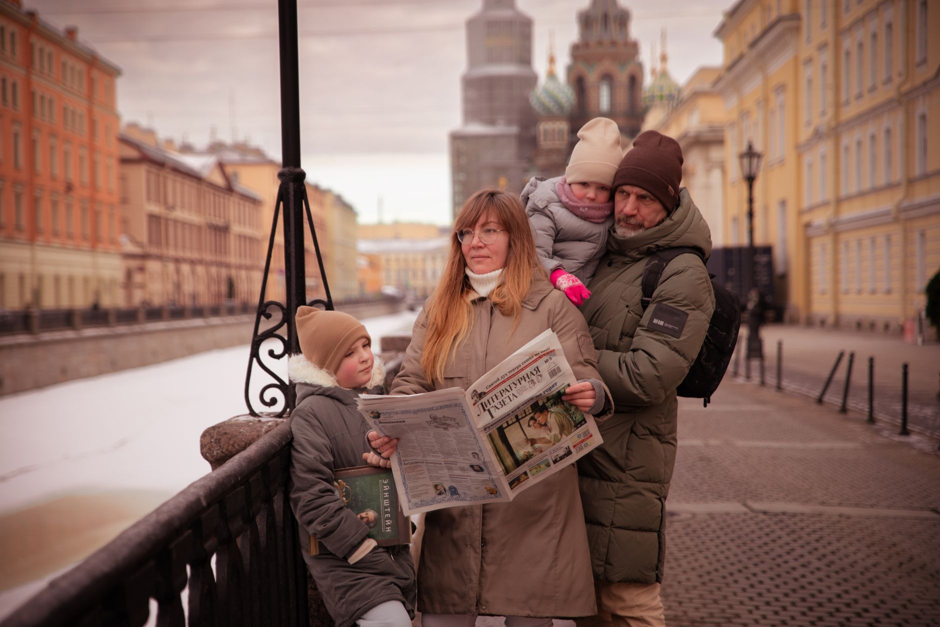 A family strolls along a canal in Saint Petersburg on a winter day, bundled up warmly against the cold. — Unlocking M