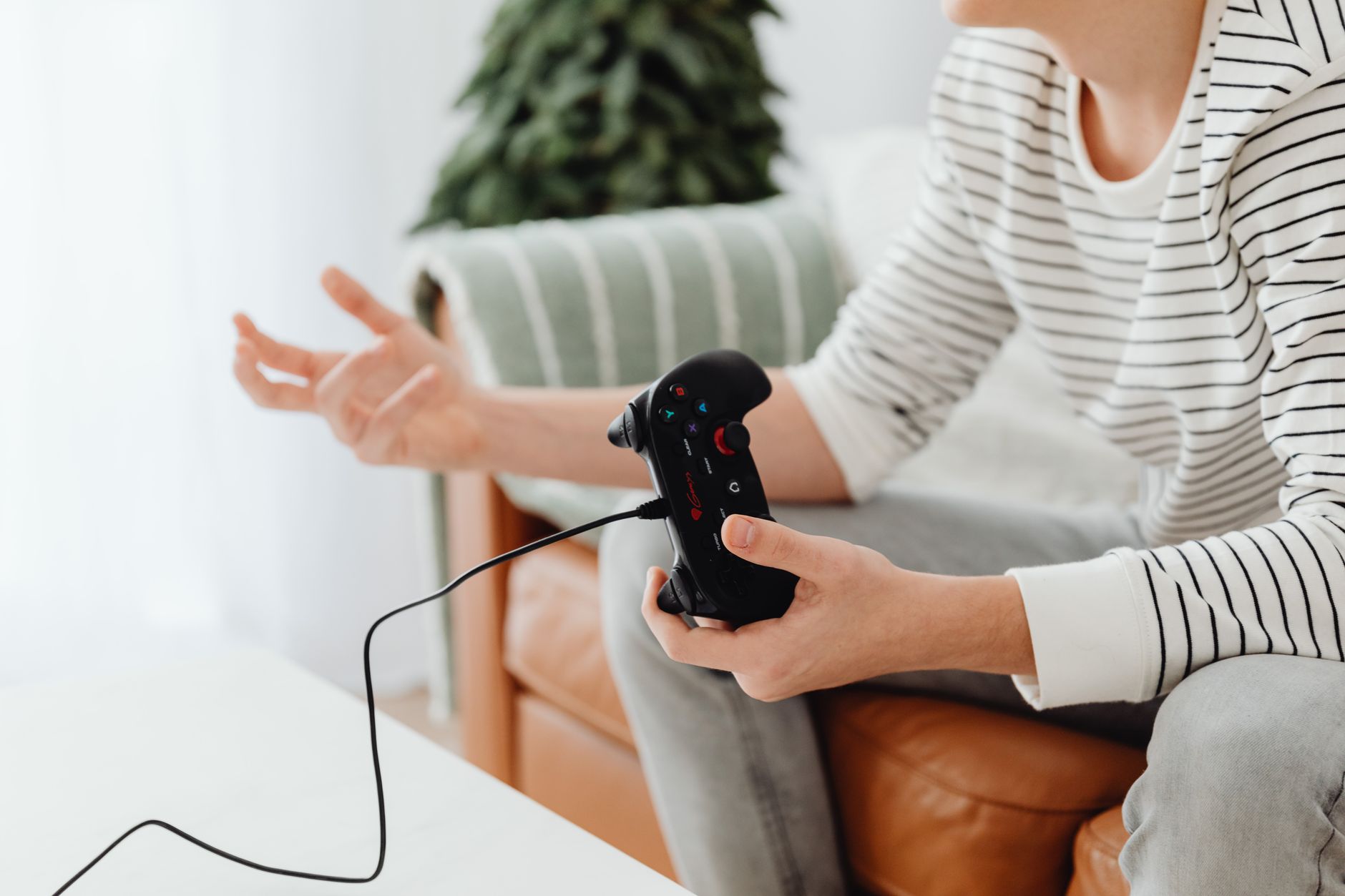 Close-up of a person playing video games at home with a wired controller on a couch. — What is a Private Toto Site?