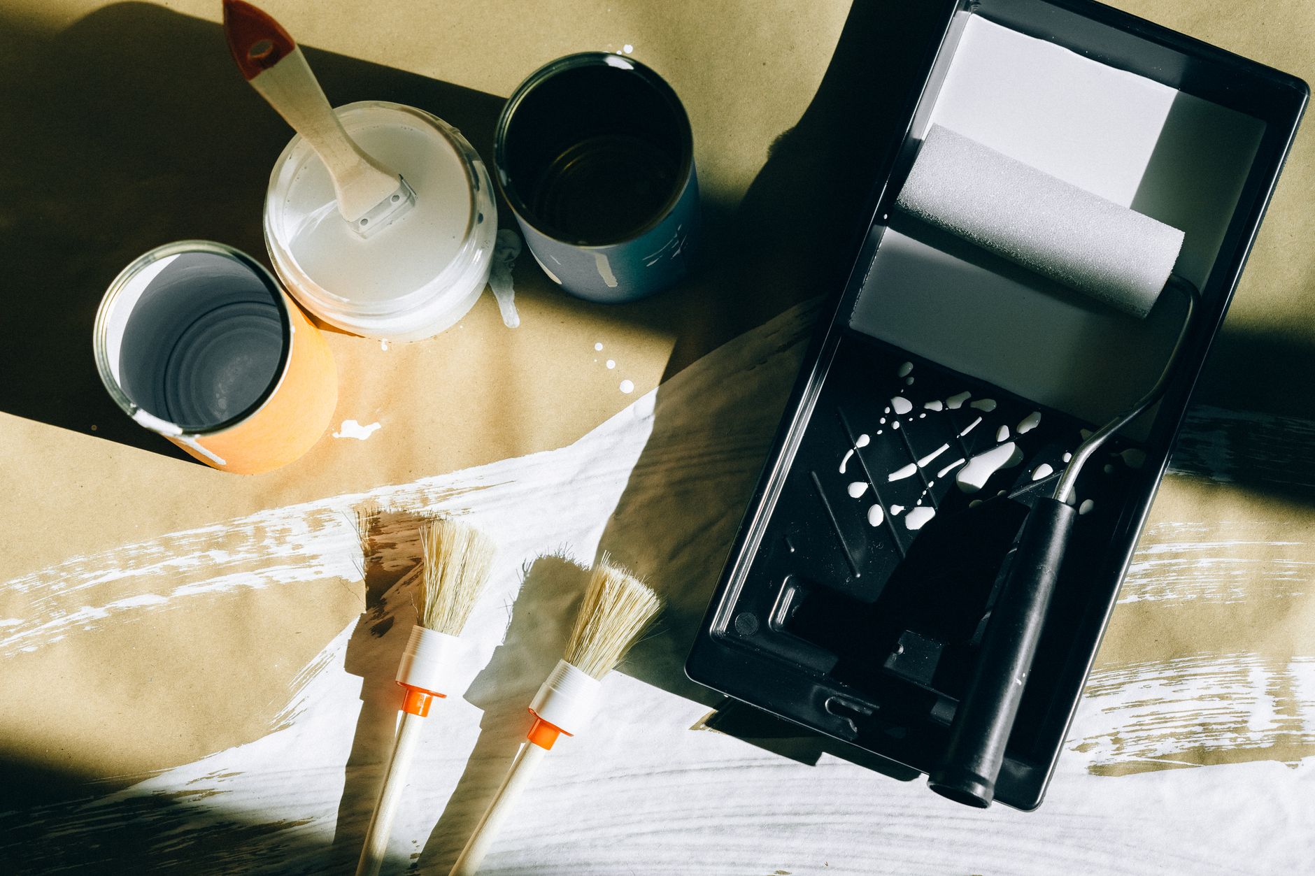 Top view of painting tools including brushes, rollers, and paint cans on paper. — The Advantages Of Mini Split Type Air-Con -