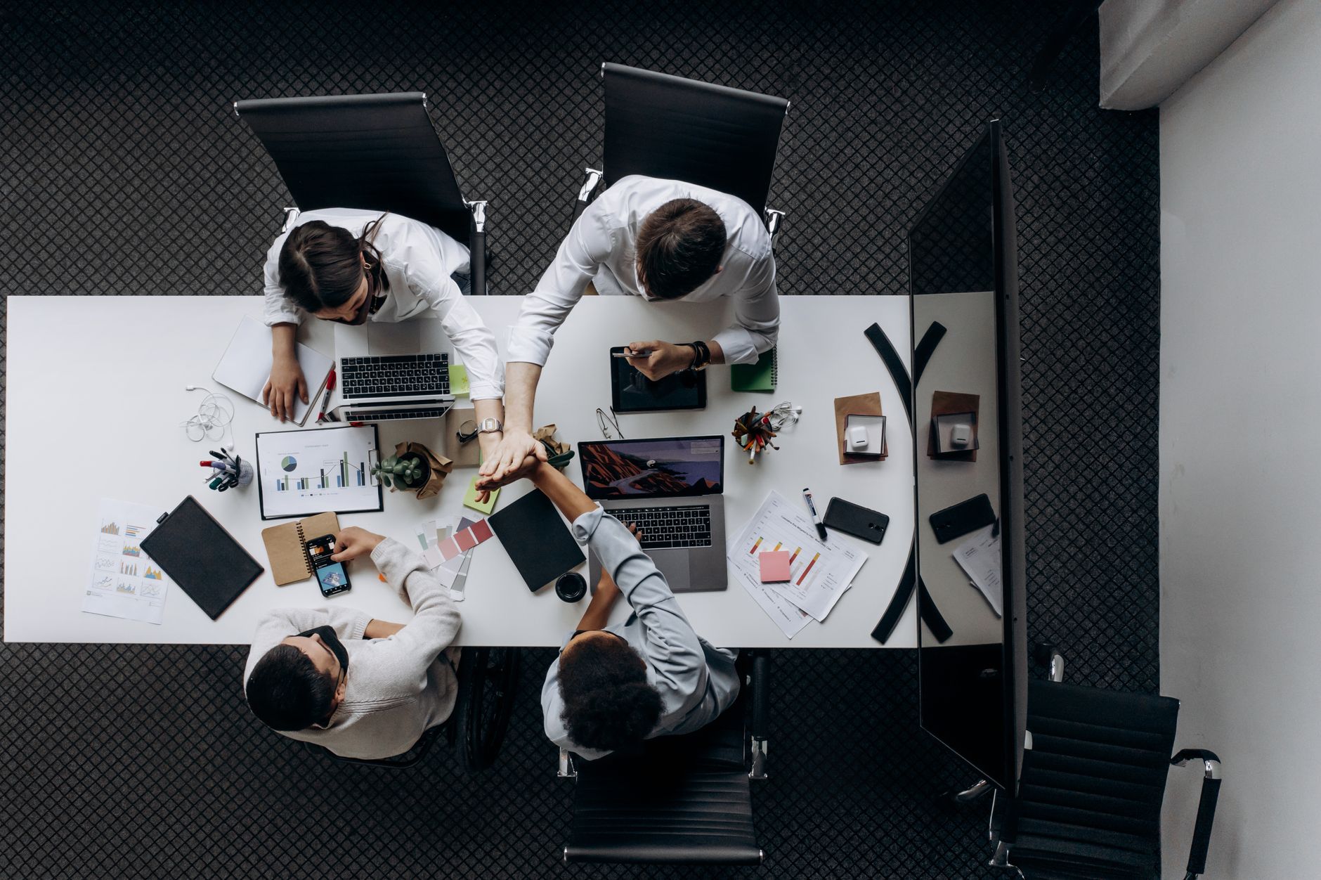 High angle view of colleagues collaborating around a conference table in a modern office setting. — The Dos and Don'ts of Buy