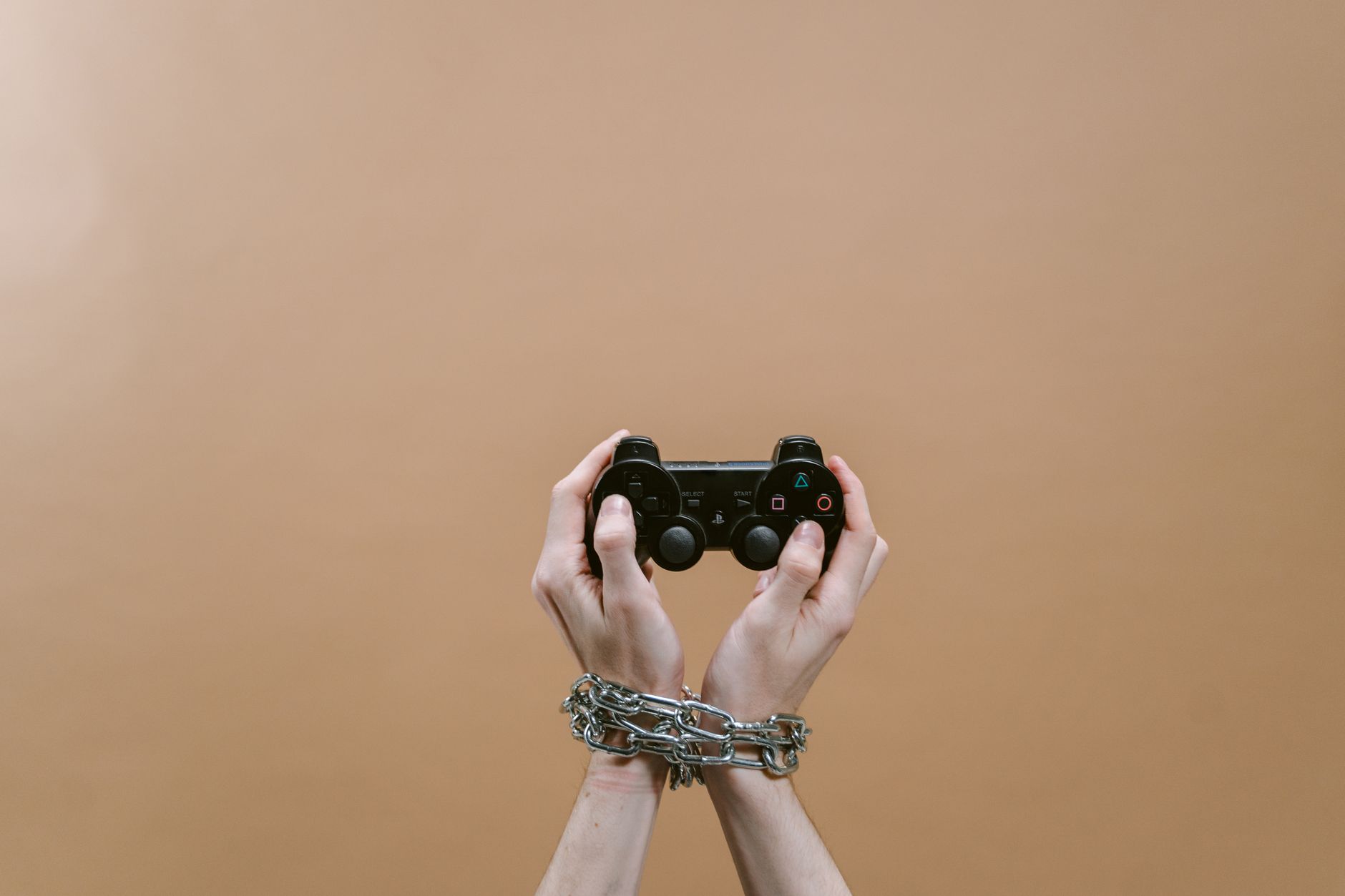 Conceptual image of hands in chains holding a game controller symbolizing gaming addiction. — The Eat-And-Run Verification Me