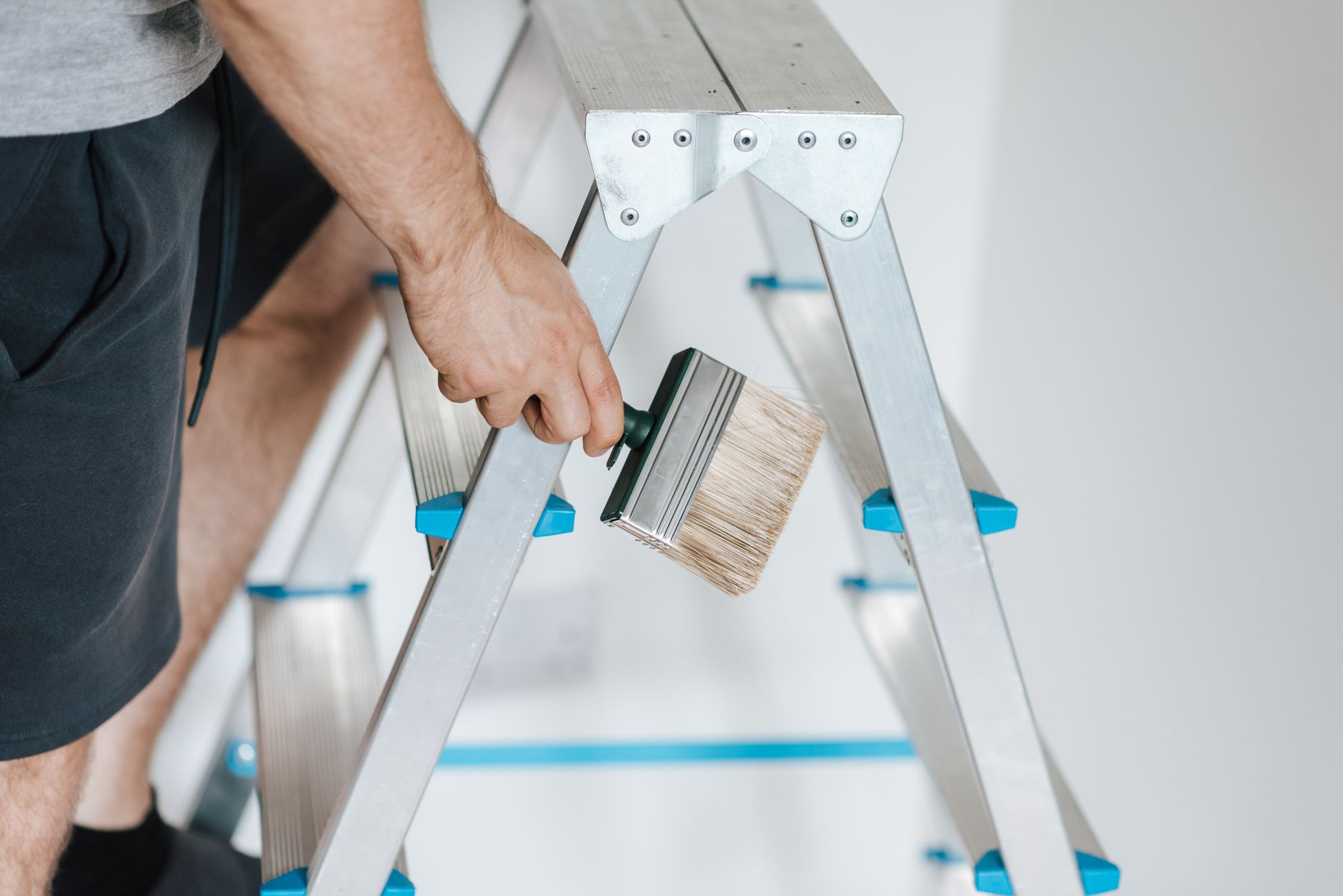Side view of crop anonymous male master standing on ladder with tool while painting walls in flat — The Most Effective Ways t
