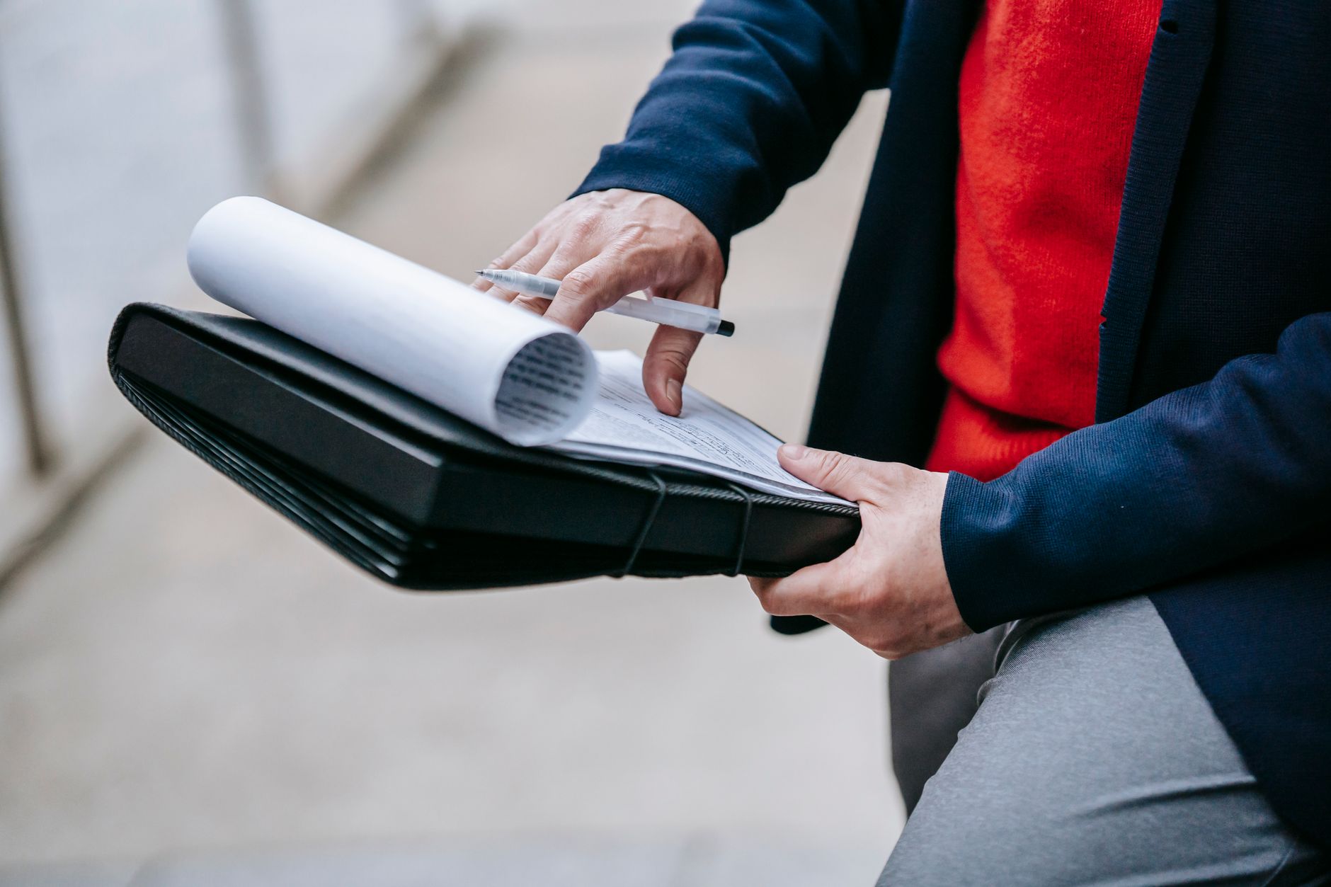 Close-up of a professional person reviewing documents outdoors. Engaged in work with focus on writing materials. — The Vision