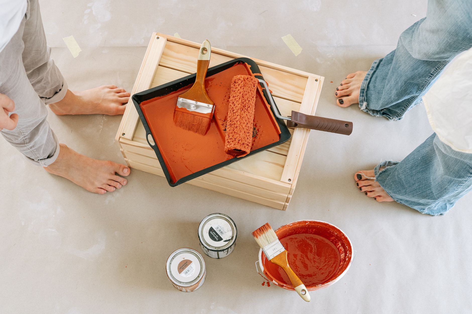 Overhead view of a renovation setup with paint, brushes, and bare feet. — There Are Many Reasons To Choose Rhinofloor Vinyl F
