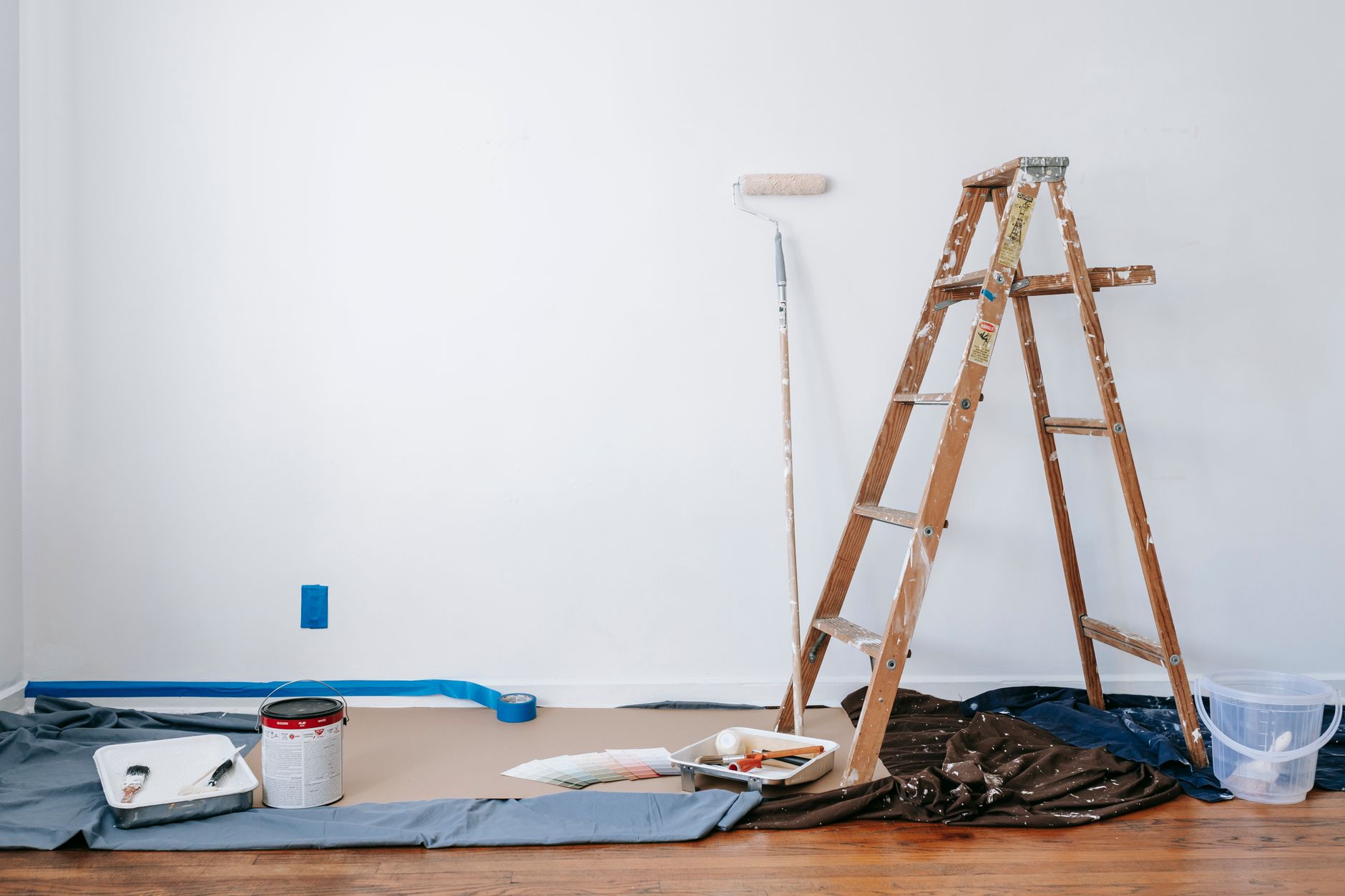 A room prepared for renovation with a ladder, paint supplies, and drop cloth. — What Types Of Edge Protectors Are There?