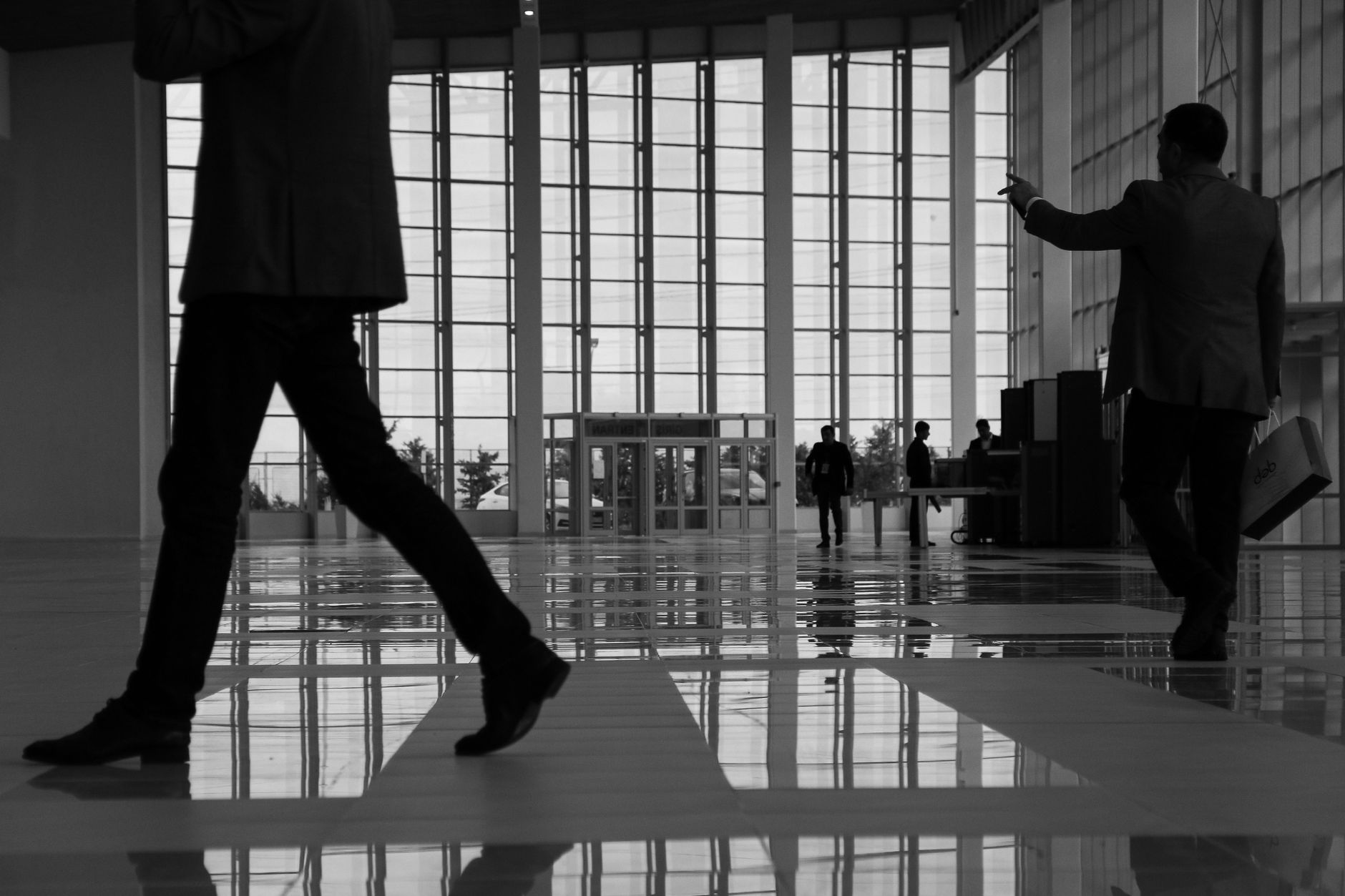 Business professionals walk through a modern, glass-paneled indoor space. — What You Need To Know About Small Business Fundin
