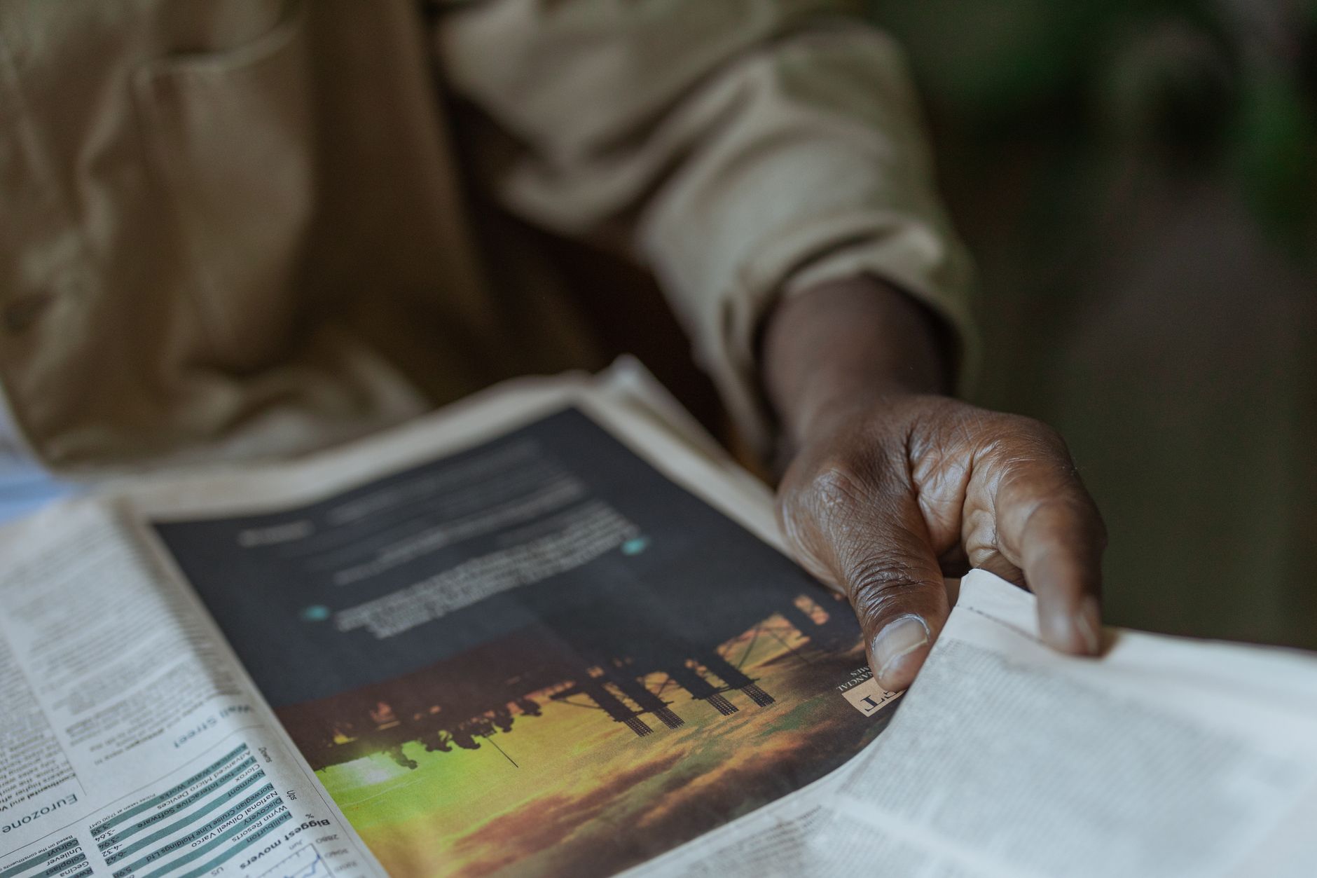 Detailed close-up of a person holding and reading a newspaper indoors. — Why 27nine Casino is the Buzz in Thailand's Gaming S