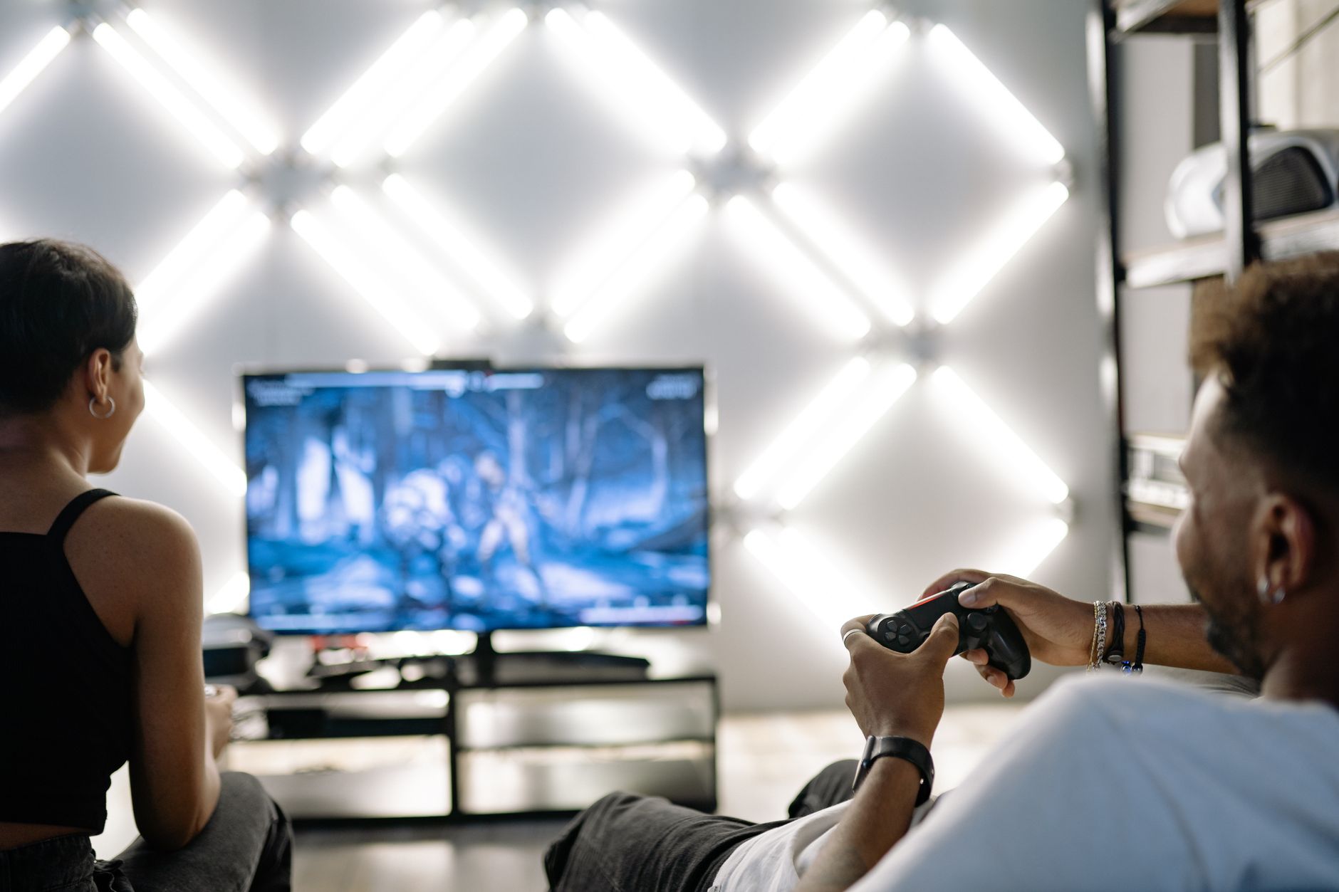 Two adults are having fun playing video games in a stylish, modern living room with LED lighting. — Why Reading Winning Formu