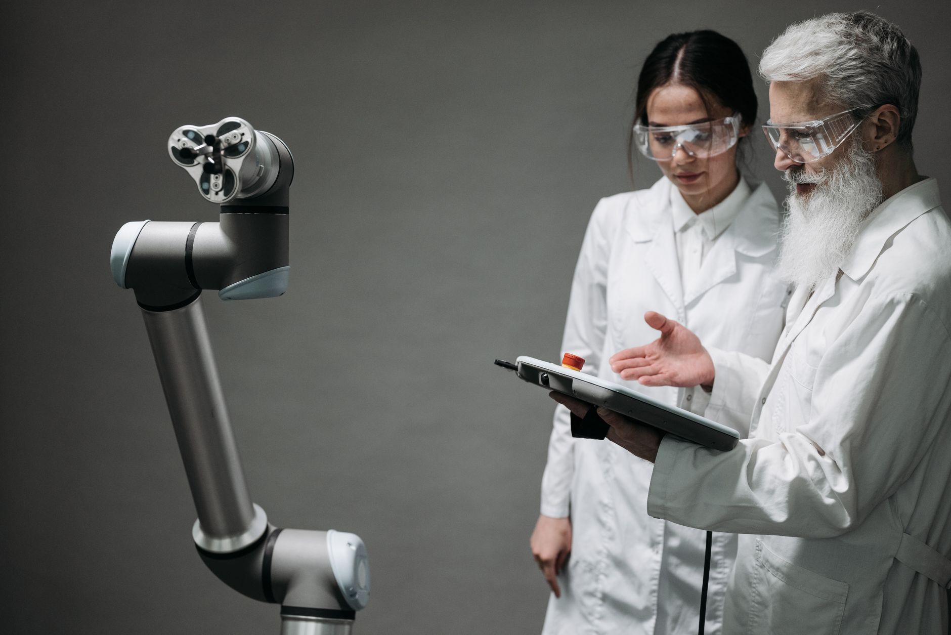 Researchers in lab coats and safety glasses engaging with a robotic arm in a lab setting. — YouTube Subscribers Increase Chan